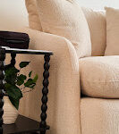 Close-up of a plush, cream-colored sofa chair in Alexis Lynne Jardine's therapy office, next to a stylish black side table with a plant.